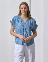 Blusa de lyocell color celeste con estampado de motivos playeros en blanco. Tiene cuello a la base con escote en V, mangas cortas con volados y detalle fruncido en mangas y espalda.