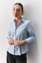 Camisa de algodón blanca, de calce relajado, con cuello clásico, mangas largas y cierre frontal con botones.