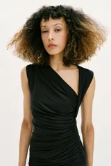 Vestido midi negro con escote asimétrico, sin mangas y detalle de drapeado delantero.