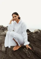 Camisa blanca de lino con cuello clásico y mangas largas abullonadas con frunces y puños elásticos.