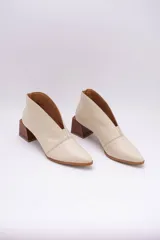 Botines de cuero color beige con diseño de tajo frontal, punta fina y taco cuadrado de madera.