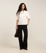 Blusa básica de mujer color negro, confeccionada en malla encorpada de algodón, con cuello redondo y mangas cortas de corte oversized con sisas desplazadas.