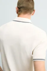 Polo de punto tejido en algodón, de corte regular fit. Presenta cuello solapa con cierre frontal de botones y manga corta, con acabados en rib y detalles de bandas a contraste en cuello y puños.