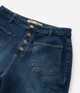 Pantalón de jean modelo flare, de tiro alto, con cierre frontal de botones a la vista y bolsillos funcionales.