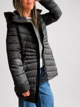 Campera puffer negra con capucha, diseño acolchado, cierre frontal y bolsillos laterales. Presenta un corte entallado y largo a la cadera.