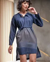 Vestido azul con estampado a cuadros, cuello con lazo y corte recto holgado con aberturas laterales.