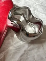 Brazalete rígido plateado con diseño irregular y abertura.