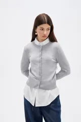 Saco de punto al cuerpo, color negro, con cuello redondo, manga larga y cierre frontal con botones pequeños.