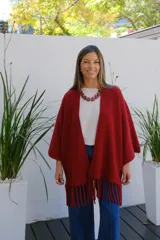 Saco abierto tipo capa en color bordó, confeccionado en tejido de punto suave, con mangas amplias y detalle de flecos en el ruedo.