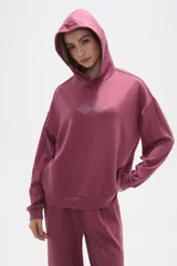 Canguro con capucha de calce holgado, color bordó, con detalle de aplique de strass en el pecho.