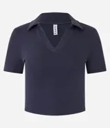 Blusa de cuello polo y manga corta, confeccionada en tejido rib de algodón con elastano. Presenta un diseño ajustado al cuerpo con escote en V y textura acanalada.