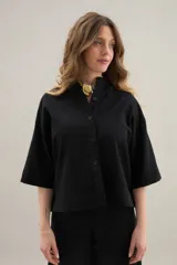 Camisa de lino de calce relajado, color negro, con cuello mao, mangas cortas y bajo redondeado con aberturas laterales.