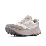 Championes de trail running New Balance modelo Hierro V9, con capellada de malla técnica en tonos claros y detalles en malva. Cuenta con entresuela Fresh Foam X para mayor amortiguación y suela Vibram para un agarre superior en terrenos irregulares.