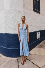 Vestido midi de algodón con estampado de lunares blancos sobre fondo celeste. Presenta cuello halter con cierre de botones y espalda descubierta, con un corte evasé fluido.