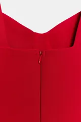 Vestido corto de color rojo con escote corazón estilo corsetero, tirantes anchos y falda con corte evasé. Cuenta con cierre de cremallera oculto en la espalda.
