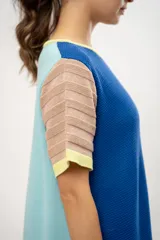 Vestido corto tejido a crochet, color azul con mangas cortas a rayas horizontales en tonos pastel y ribete amarillo.