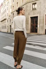 Pantalón de tiro medio con diseño bombacho, frunces delanteros y pierna abullonada con puños ajustados. Incluye bolsillos frontales y un cinturón decorativo con cadena metálica.