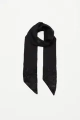 Pañuelo tipo corbatín de símil seda, color negro, con diseño largo y angosto. Presenta detalles de lentejuelas bordadas en los extremos que aportan brillo y textura.
