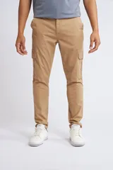 Pantalón cargo de corte slim, color beige, con cierre y botón frontal, bolsillos laterales tipo cargo y terminación recta sin puños.