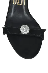 Sandalia negra de gamuza con taco aguja, tira delgada sobre los dedos con detalle de esfera brillante y tira fina que se ata al tobillo.