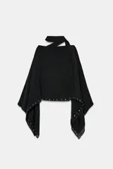 Capa negra de cuello redondo con detalle de tachas plateadas en el ruedo y pañuelo tipo bufanda integrado en el mismo tejido.