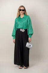 Cartera tipo baúl color plateado metalizado, con solapa y detalle de aplique piramidal metálico en el centro. Cuenta con asa corta de mano y correa para llevar al hombro.