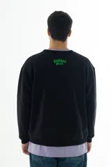 Buzo negro de algodón con cuello redondo y puños acanalados. Estampado frontal con un personaje de caricatura y el texto "HOME ALONE" en verde.