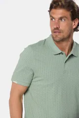 Remera polo de piqué en color azul con estampado de mini print geométrico en toda la prenda. Presenta cuello clásico, cierre frontal con botones personalizados y logo bordado en el pecho.