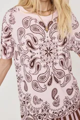 Remera de manga corta color rosado con estampado de diseño paisley en marrón, de corte holgado y cuello redondo.