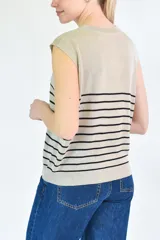 Musculosa de tejido de punto con diseño a rayas horizontales oscuras sobre base color crema, cuello redondo y corte recto.
