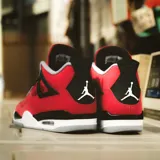 Championes Air Jordan 4 Retro en color rojo con detalles en negro, gris y blanco, confeccionados con paneles de malla y refuerzos plásticos característicos del modelo.