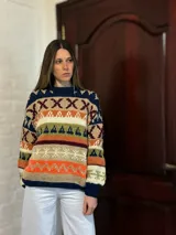 Sweater de lana merino con estampado Fair Isle en tonos azul marino, beige, naranja, verde oliva y bordó. Tiene cuello redondo y mangas largas.