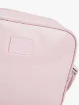 Cartera tipo bandolera de Tommy Jeans con acabado brillante y liso. Presenta un diseño compacto con cierre de cremallera y una insignia con el logo de la marca grabado en el frente.