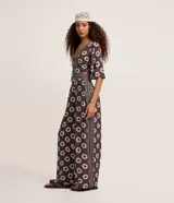 Mono largo de viscosa con estampado gráfico de soles, escote en V profundo, mangas cortas amplias y aberturas laterales en la cintura.