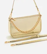 Cartera tipo shoulder baguette de tamaño pequeño, confeccionada en poliuretano con textura símil reptil. Presenta un diseño estructurado con cierre superior, correa larga ajustable y removible, y una cadena metálica decorativa en la parte frontal.