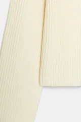 Jersey de punto acanalado en color crudo, con cuello en pico cruzado y manga larga. Presenta un diseño de corte recto y textura acanalada en toda la prenda.
