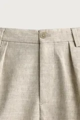 Pantalón relaxed fit de color blanco off-white, confeccionado en tejido con lino. Cuenta con pliegues frontales en la cintura, bolsillos delanteros y cierre frontal con cremallera y botón.