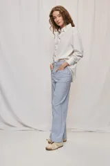 Pantalón de pierna ancha y tiro medio con diseño de rayas verticales blancas y azules. Cuenta con bolsillos delanteros amplios y cierre frontal con botón y cremallera.