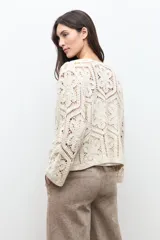 Chaqueta tejida a crochet en color beige claro, de diseño abierto y manga larga con patrones geométricos calados.