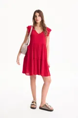 Vestido corto de viscosa color beige, sin mangas con volados en las sisas, escote en V y diseño escalonado.