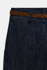 Pantalón chino de tiro bajo color marrón oscuro, con pernera recta y bajo con vuelta. Incluye un cinturón trenzado delgado de color marrón claro. Cuenta con bolsillos delanteros y cierre frontal con cremallera y botón.