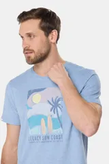 Remera de manga corta color gris con estampado de paisaje costero con palmeras y tablas de surf.