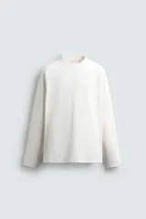 Camiseta de manga larga con corte relajado, confeccionada en tejido compacto de algodón. Presenta cuello redondo acabado en rib y detalle de costura central en la espalda.