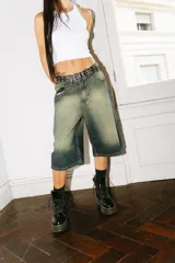 Bermuda de jean estilo baggy con lavado verde desgastado. Presenta grandes bolsillos traseros con bordados en hilo rojo que simulan caracteres chinos.
