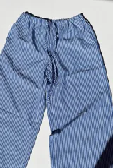 Pantalón palazzo celeste a rayas verticales blancas, de tiro alto y corte holgado.