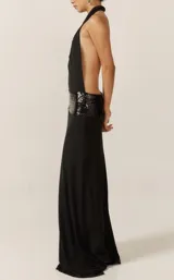 Vestido largo negro de fiesta, con escote halter drapeado, espalda descubierta y faja de lentejuelas negras en la cintura.