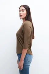 Remera de manga tres cuartos color verde oliva, con cuello redondo y detalles de vainillas (encaje o perforado) en la costura de la sisa.