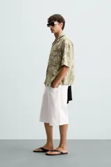 Camisa de manga corta y corte relajado confeccionada en tejido de algodón con diseño jacquard floral. Presenta cuello bowling, un bolsillo de plastrón en el pecho y cierre frontal con botones.