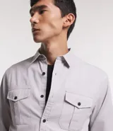 Camisa verde militar de manga larga en sarga de algodón, con cuello clásico, cierre frontal abotonado y dos bolsillos con solapa abotonada en el pecho.