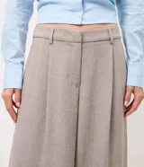 Pantalón de sastrería de corte ancho y recto, color gris, con cintura doble estructurada y removible, pinzas frontales y bolsillos.